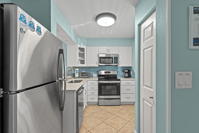 502 Gulf Shore Dr Unit 215, Destin, FL 32541 - kitchen featuring appliances with stainless steel finishes, a sink, light countertops, white cabinetry, and light tile patterned flooring