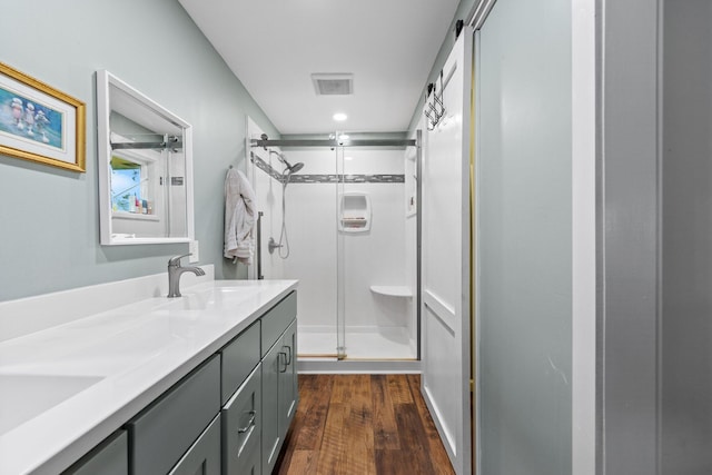 207 Oakwood Cir, Niceville, FL 32578 - bathroom featuring a stall shower, wood finished floors, double vanity, and recessed lighting