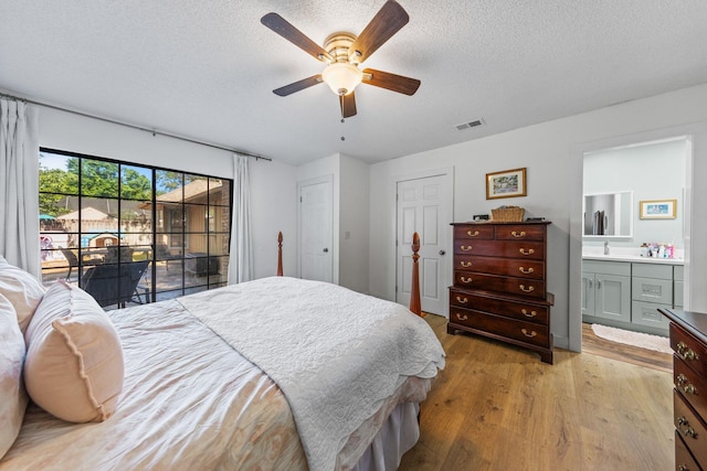207 Oakwood Cir, Niceville, FL 32578 - bedroom featuring light wood-style flooring, a textured ceiling, ensuite bath, a ceiling fan, and access to outside