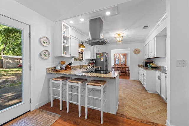 207 Oakwood Cir, Niceville, FL 32578 - kitchen featuring stainless steel appliances, island exhaust hood, a peninsula, white cabinets, and ornamental molding