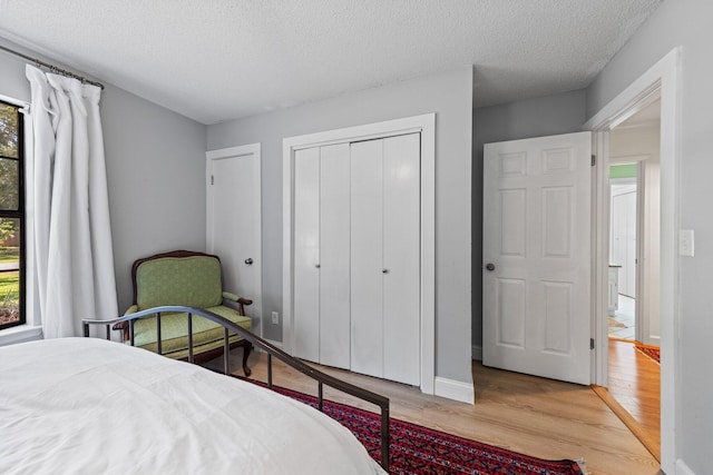 207 Oakwood Cir, Niceville, FL 32578 - bedroom featuring light wood finished floors, a textured ceiling, a closet, and baseboards