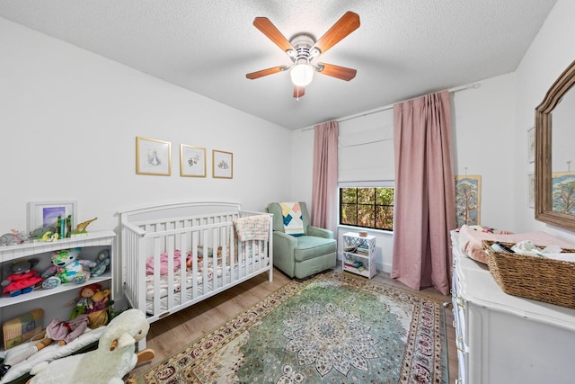 207 Oakwood Cir, Niceville, FL 32578 - bedroom with a nursery area, wood finished floors, ceiling fan, and a textured ceiling