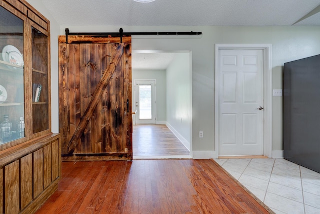 4236 Edge Perry Rd, Crestview, FL 32539 - empty room featuring light wood-style floors, a barn door, baseboards, and a textured ceiling