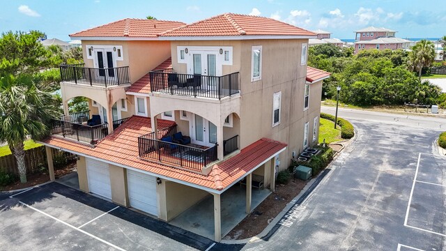142 Southfields Rd, Panama City Beach, FL 32413 - back of house with french doors, a balcony, stucco siding, and asphalt driveway