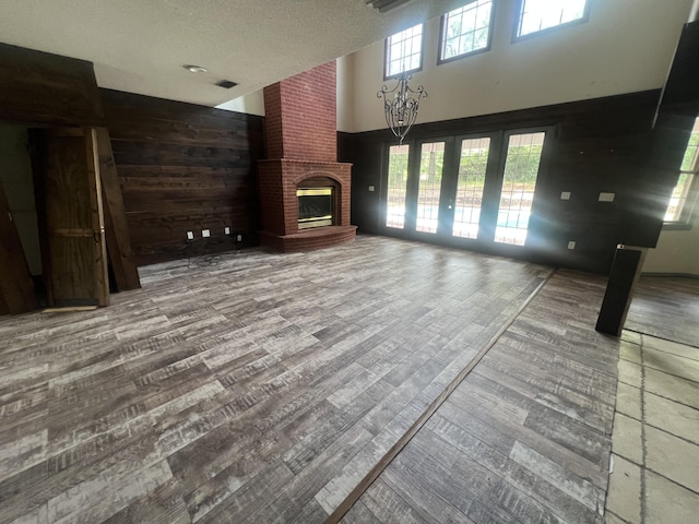 4932 Joiner Cir, Milton, FL 32583 - unfurnished living room with wood finished floors, a brick fireplace, a towering ceiling, a textured ceiling, and wooden walls