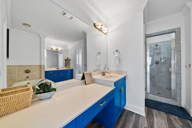 512 Dement Cir Apt F, Panama City Beach, FL 32407 - bathroom featuring a stall shower, two vanities, wood finished floors, a bath, and a textured ceiling