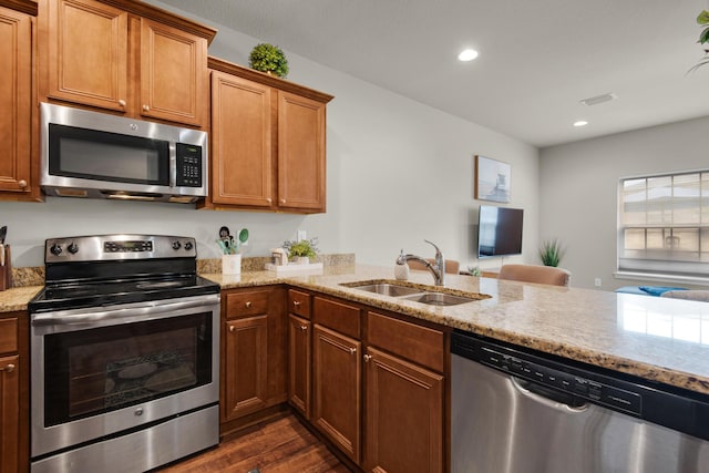 2065 Wilsons Plover Cir, Navarre, FL 32566 - kitchen with stainless steel appliances, a sink, light stone counters, dark wood-type flooring, and brown cabinetry