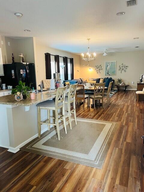 115 Lilly Bell Ln, Freeport, FL 32439 - kitchen featuring freestanding refrigerator, a breakfast bar, dark wood-type flooring, and open floor plan