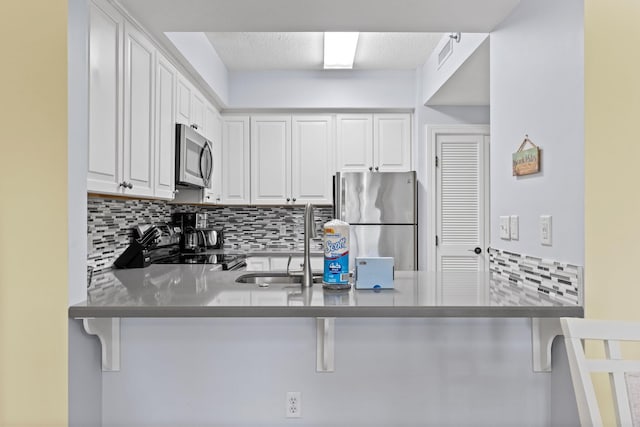 515 Topsl Beach Blvd # 401, Miramar Beach, FL 32550 - kitchen featuring stainless steel appliances, decorative backsplash, a sink, a peninsula, and white cabinetry