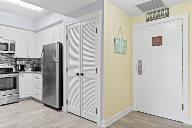 515 Topsl Beach Blvd # 401, Miramar Beach, FL 32550 - kitchen with stainless steel appliances, light wood finished floors, white cabinets, tasteful backsplash, and baseboards