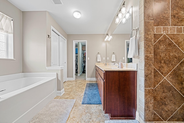 5416 Mill Brook Ln, Crestview, FL 32539 - bathroom featuring double vanity, a garden tub, a spacious closet, and baseboards