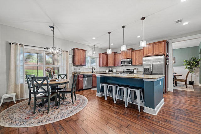 5416 Mill Brook Ln, Crestview, FL 32539 - kitchen featuring appliances with stainless steel finishes, a kitchen island, a chandelier, dark wood-type flooring, and a breakfast bar area
