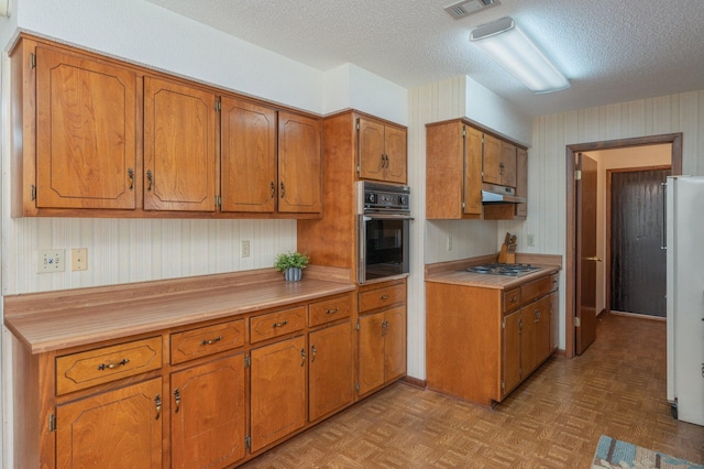 5951 N Meadow Ln, Crestview, FL 32539 - kitchen with wall oven, under cabinet range hood, brown cabinets, and a textured ceiling