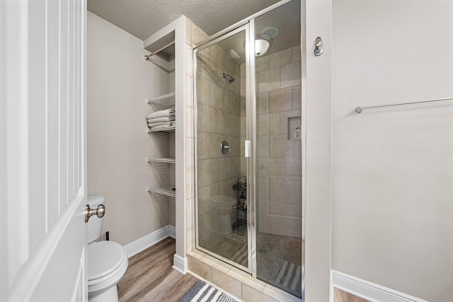 64 Crossing Ln Unit E, Santa Rosa Beach, FL 32459 - bathroom featuring toilet, a shower stall, baseboards, wood finished floors, and a textured ceiling
