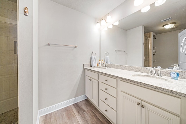 64 Crossing Ln Unit E, Santa Rosa Beach, FL 32459 - bathroom with double vanity, tiled shower, wood finished floors, and baseboards