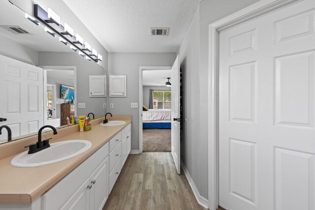 5123 Whitehurst Ln, Crestview, FL 32536 - ensuite bathroom with wood finished floors, double vanity, a ceiling fan, and a textured ceiling