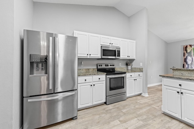 5123 Whitehurst Ln, Crestview, FL 32536 - kitchen with appliances with stainless steel finishes, lofted ceiling, white cabinetry, stone counters, and light wood-style floors