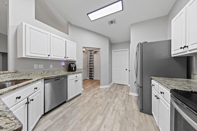 5123 Whitehurst Ln, Crestview, FL 32536 - kitchen with stainless steel dishwasher, white cabinetry, light wood finished floors, vaulted ceiling, and light stone counters