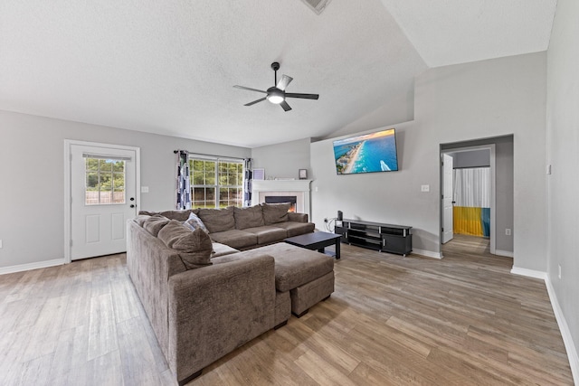 5123 Whitehurst Ln, Crestview, FL 32536 - living area with light wood finished floors, ceiling fan, lofted ceiling, a glass covered fireplace, and a textured ceiling