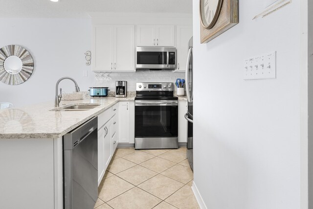 2606 Scenic Gulf Dr Unit 2412, Miramar Beach, FL 32550 - kitchen with stainless steel appliances, a sink, a peninsula, white cabinets, and light tile patterned floors