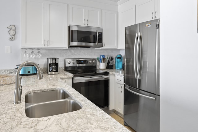 2606 Scenic Gulf Dr Unit 2412, Miramar Beach, FL 32550 - kitchen with appliances with stainless steel finishes, a sink, white cabinetry, tasteful backsplash, and light stone countertops
