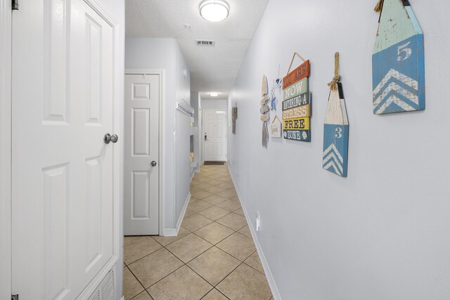 2606 Scenic Gulf Dr Unit 2412, Miramar Beach, FL 32550 - corridor with light tile patterned floors, baseboards, and a textured ceiling
