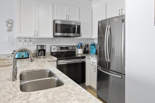 2606 Scenic Gulf Dr Unit 2412, Miramar Beach, FL 32550 - kitchen with stainless steel appliances, a sink, white cabinetry, decorative backsplash, and light stone counters