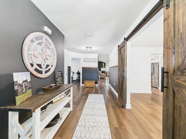 5740 Marigold Loop, Crestview, FL 32539 - corridor featuring a barn door, wood finished floors, baseboards, and a textured ceiling