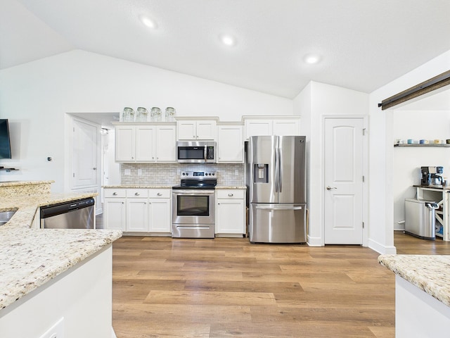 5740 Marigold Loop, Crestview, FL 32539 - kitchen featuring stainless steel appliances, vaulted ceiling, white cabinets, decorative backsplash, and light wood-type flooring