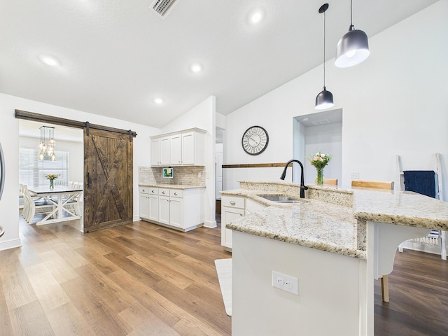 5740 Marigold Loop, Crestview, FL 32539 - kitchen with a sink, lofted ceiling, a barn door, a kitchen bar, and light wood-style flooring