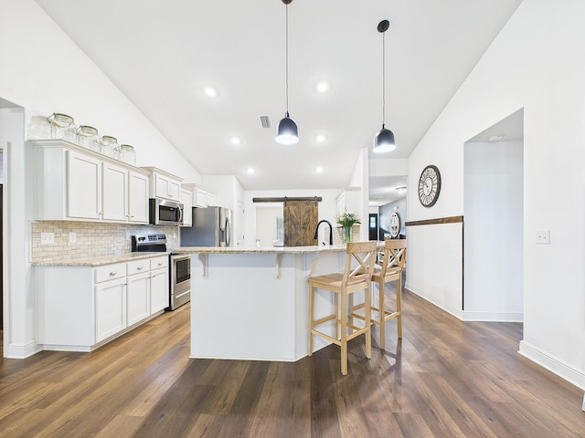 5740 Marigold Loop, Crestview, FL 32539 - kitchen featuring stainless steel appliances, vaulted ceiling, white cabinets, dark wood-type flooring, and a kitchen bar