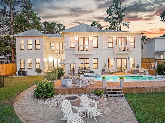 92 Carolyn Ln, Santa Rosa Beach, FL 32459 - back of house at dusk featuring a balcony, french doors, an outdoor living space with a fire pit, and a wooden deck