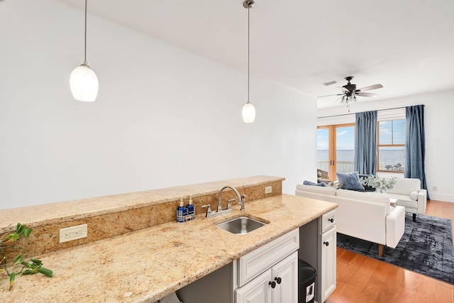 92 Carolyn Ln, Santa Rosa Beach, FL 32459 - kitchen featuring a sink, wood finished floors, light stone counters, hanging light fixtures, and french doors
