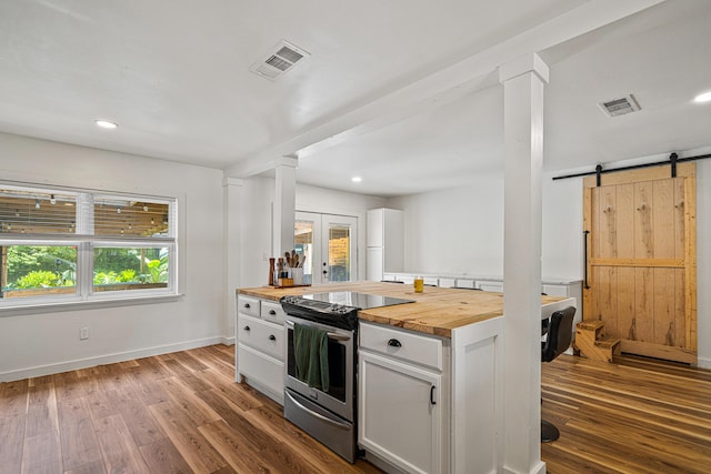 29 SE Alexandra Pl, Fort Walton Beach, FL 32548 - kitchen featuring wooden counters, stainless steel range with electric stovetop, a barn door, white cabinetry, and wood finished floors