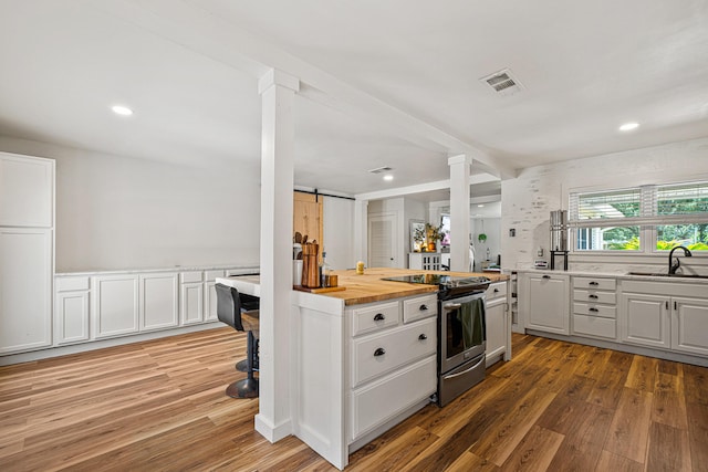 29 SE Alexandra Pl, Fort Walton Beach, FL 32548 - kitchen with electric range, ornate columns, a sink, light wood finished floors, and white cabinets