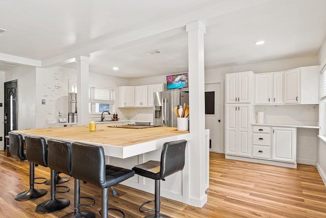 29 SE Alexandra Pl, Fort Walton Beach, FL 32548 - kitchen featuring decorative columns, butcher block countertops, a sink, a kitchen breakfast bar, and white cabinetry
