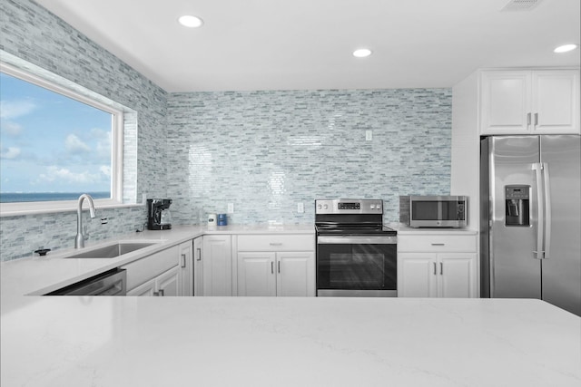 14351 State Highway 20, Niceville, FL 32578 - kitchen with appliances with stainless steel finishes, backsplash, recessed lighting, white cabinetry, and light stone counters