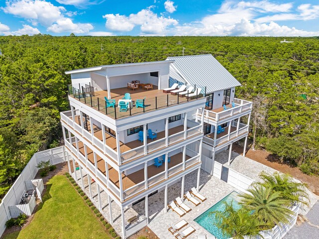 7570 E County Highway 30a, Watersound, FL 32461 - back of property featuring a view of trees, a balcony, a fenced backyard, a standing seam roof, and a patio