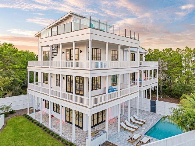 7570 E County Highway 30a, Watersound, FL 32461 - back of property at dusk with a balcony, a fenced backyard, and a patio area