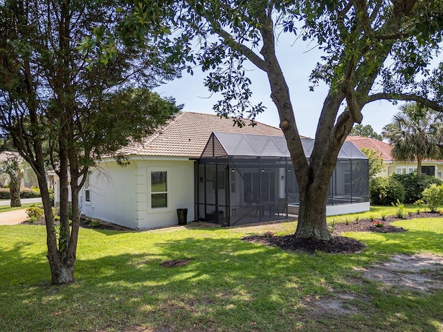 359 Indigo Loop, Miramar Beach, FL 32550 - rear view of house featuring a tile roof, a lawn, stucco siding, and glass enclosure