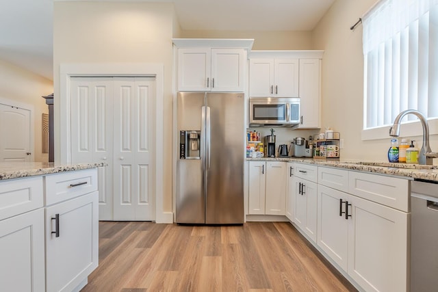 409 Hideaway Ln, Niceville, FL 32578 - kitchen with appliances with stainless steel finishes, light wood-style flooring, white cabinetry, and light stone countertops
