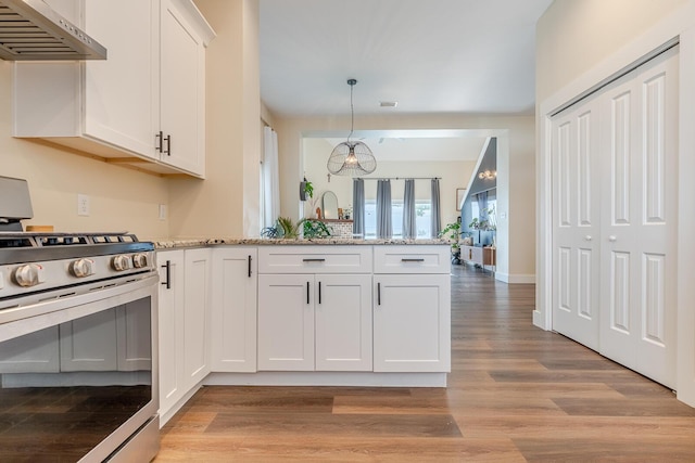 409 Hideaway Ln, Niceville, FL 32578 - kitchen with gas stove, under cabinet range hood, a peninsula, white cabinets, and light wood-style floors