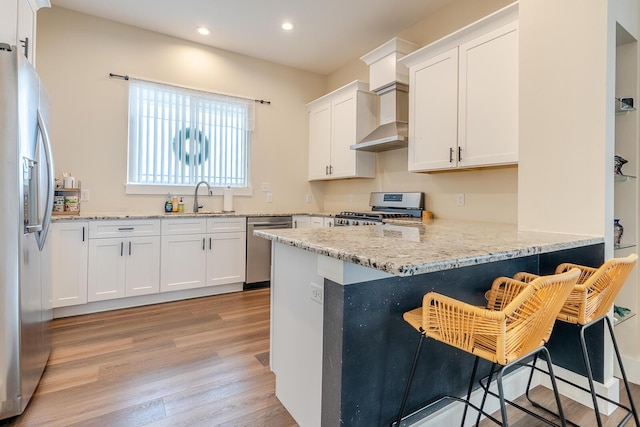 409 Hideaway Ln, Niceville, FL 32578 - kitchen featuring stainless steel appliances, wall chimney range hood, recessed lighting, light wood-style flooring, and a peninsula