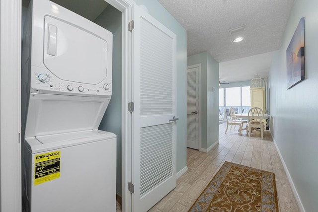 1515 SE Miracle Strip Pkwy Unit 613, Fort Walton Beach, FL 32548 - laundry room with stacked washer and clothes dryer, a textured ceiling, baseboards, and light wood-type flooring