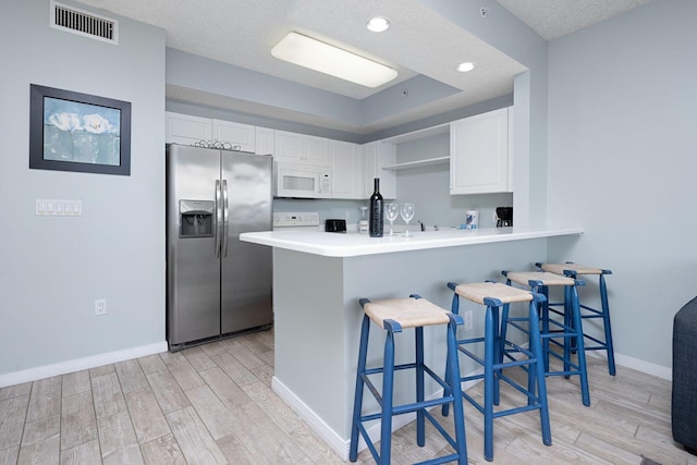 1515 SE Miracle Strip Pkwy Unit 613, Fort Walton Beach, FL 32548 - kitchen featuring white microwave, stainless steel fridge with ice dispenser, light wood-style flooring, a kitchen bar, and recessed lighting