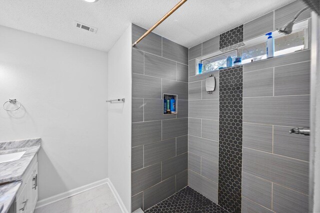 4887 Martina Way, Gulf Breeze, FL 32563 - bathroom with vanity, tiled shower, baseboards, and a textured ceiling
