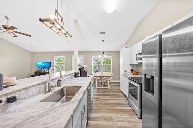 4887 Martina Way, Gulf Breeze, FL 32563 - kitchen featuring appliances with stainless steel finishes, a sink, light wood-style floors, light stone countertops, and hanging light fixtures