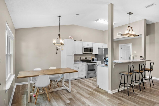 4887 Martina Way, Gulf Breeze, FL 32563 - kitchen featuring appliances with stainless steel finishes, light wood finished floors, a breakfast bar, lofted ceiling, and baseboards