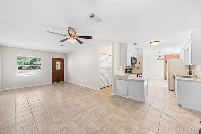 814 Tuxedo Dr, Fort Walton Beach, FL 32547 - kitchen with stainless steel electric range, black microwave, ceiling fan, tile countertops, and freestanding refrigerator