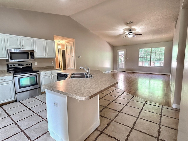 4868 Orlimar St, Crestview, FL 32536 - kitchen with stainless steel appliances, vaulted ceiling, light countertops, white cabinets, and open floor plan